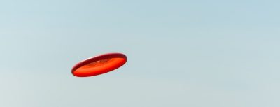 Frisbee-Ultimate - An orange frisbee flying in the air with mountains in the background